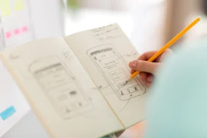 person with notebook sketching a mobile interface